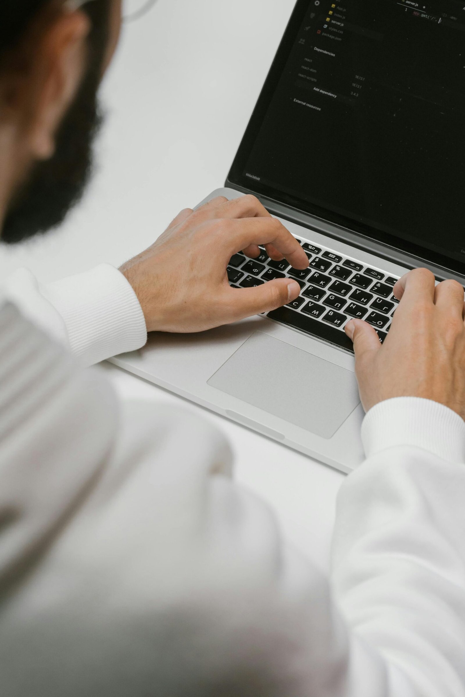 A male programmer intensely typing code on a laptop, showcasing modern technology and software development.